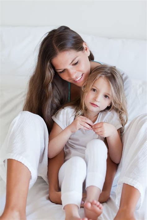 portrait of a mother and her daughter posing on a bed stock image