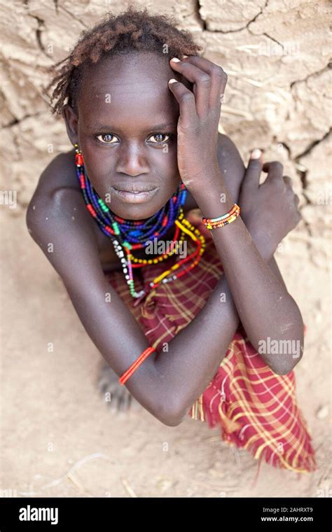 portrait of a girl from dassanech tribe in front of a cracked walls of