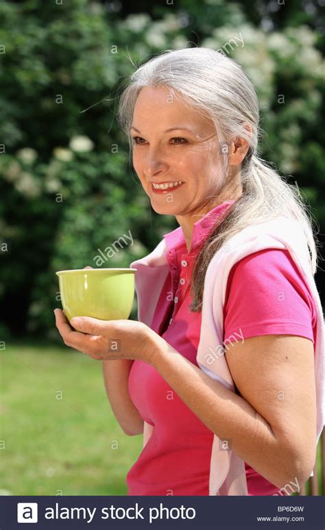 ältere frau entspannend im garten eine tasse kaffee trinken stockfoto