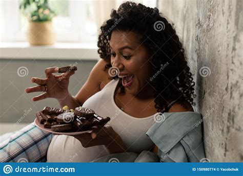happy pregnant woman crowing eating chocolate cookies