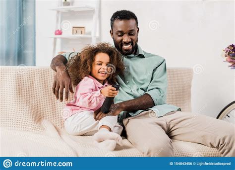 African American Dad And Daughter Watching Tv Together In