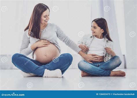 Cheerful Pregnant Woman Touching Belly Of Her Daughter Stock Image