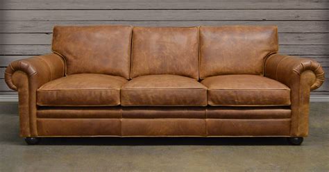 brown leather couch sitting  front   wooden wall