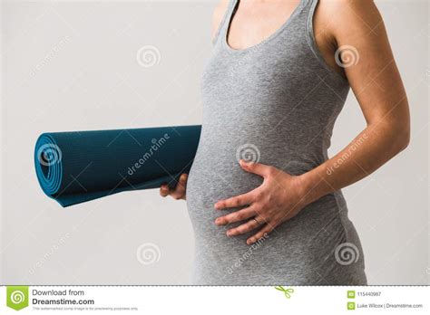 jonge vrouw  vroege zwangerschap met gerolde mat onder haar wapen die naar prenatale