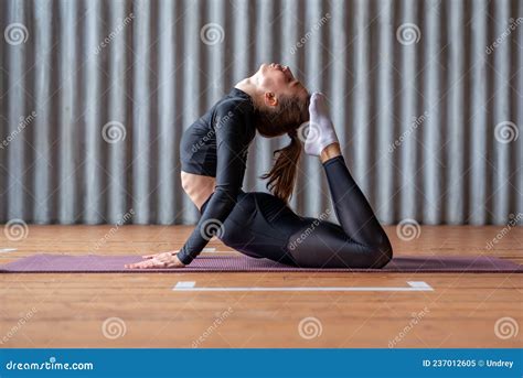 Woman Working Out At Home Arching Her Back And Reaching Her Toes For
