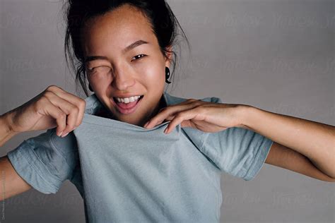 korean girl taking off t shirt and squinting at camera by danil nevsky