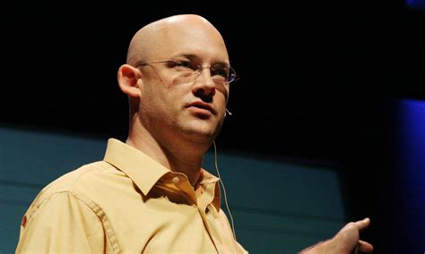 bald man wearing glasses   yellow shirt  giving  speech