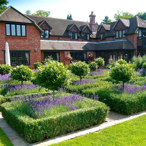 large brick house surrounded  lush green grass  purple flowers   front yard