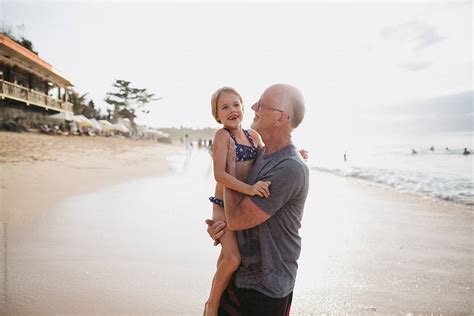 active happy grandpa having fun with granddaughter on beach vac by
