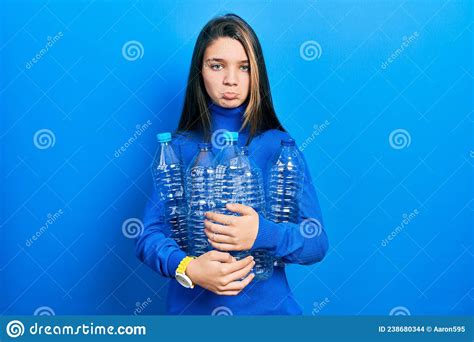 Young Brunette Girl Holding Recycling Plastic Bottles Depressed And