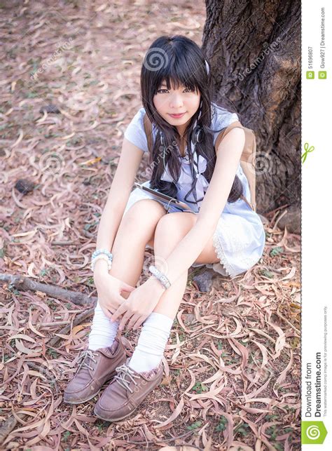 A Cute Asian Thai Girl Is Sitting With Her Knees Up Under