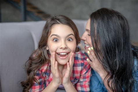Dark Haired Mom Telling Something Interesting To Her Surprised Daughter