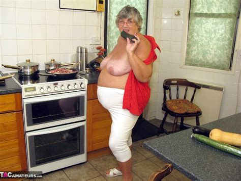 big fat grandma cooking before she takes off her red blouse and squeeze a huge cucumber between