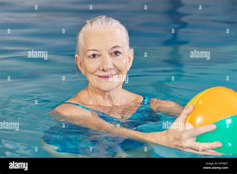 Happy Senior Woman With Water Ball In Swimming Pool Doing Aqua Fitness
