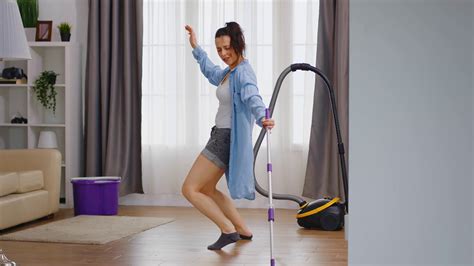 happy woman dancing while cleaning the floor house with mop stock