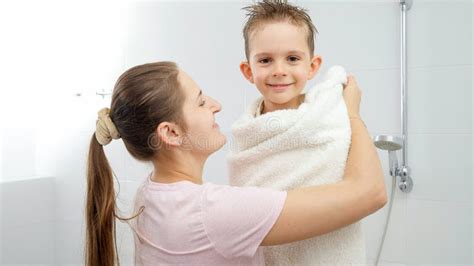 Happy Smiling Mother Hugging And Covering Her Son In Bath Towel After