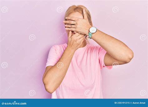 Young Blonde Woman Wearing Casual Pink T Shirt Covering Eyes And Mouth