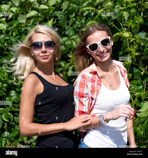 Two Girls Posing In The Green Bushes Glasses Blonde And Brunette