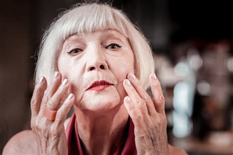 gentle blonde senior lady covering skin on her face stock image image