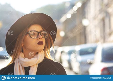 urban portrait of gorgeous blonde model with red lips wearing glasses