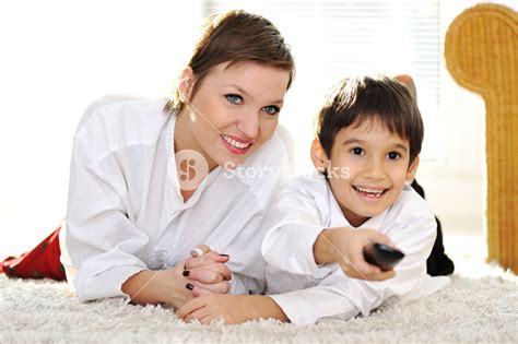 mom with son lying on floor and watching tv using remote control