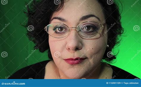 Mature Latina Woman Puts On Glasses With Green Background Stock Video