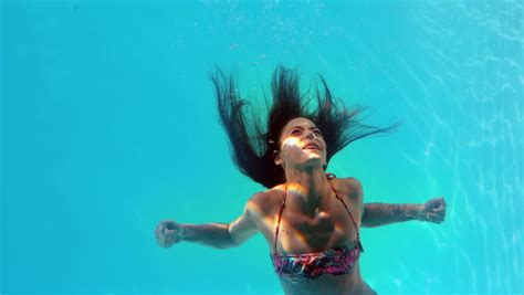 brunette swimming underwater in the pool in slow motion