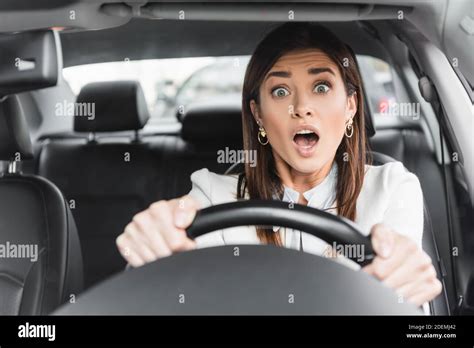 frightened woman screaming while driving car on blurred foreground