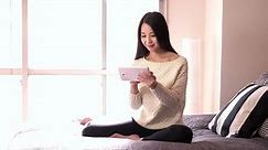 Beautiful young Asian woman relaxing in bedroom at home and smiling, pretty Japanese girl using ipad digital tablet for internet and email. Happy people, technology, lifestyle, fun and leisure