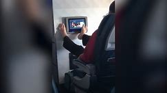 Airline passenger uses TV with his bare feet