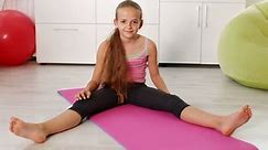 Young girl exercising at home - doing stretching gymnastic exercises