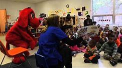 Clifford the Big Red Dog gives books to children