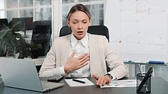 Breathing problems, chest pain, panic attack at work. Business woman has difficulty breathing, female hand touches chest. Heart attack, thoracic osteochondrosis, asthma, osteochondrosis concepts.