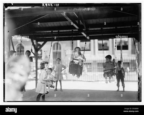 Children play on swings at the Seward Park Playground in New York City ...