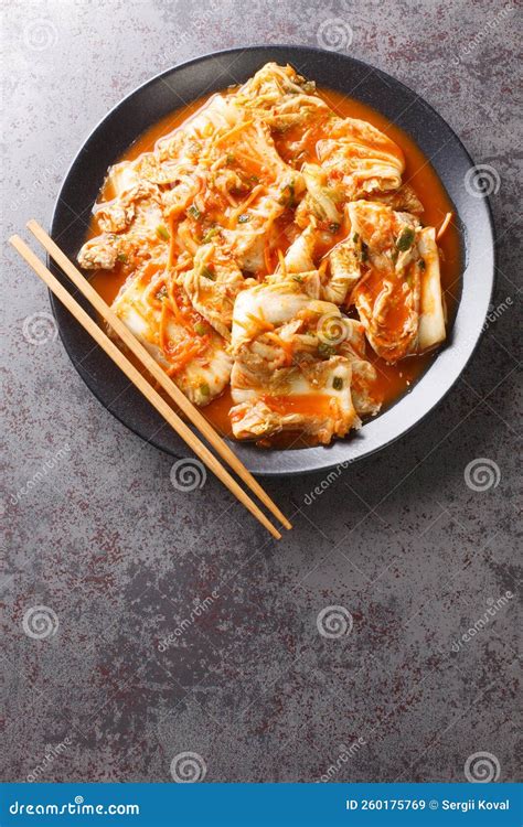 Eating Kimchi Cabbage in a Bowl with Chopsticks, Korean Food Close-up in a Black Dish. Vertical ...