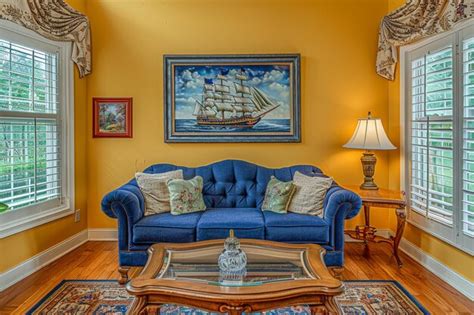 A living room with a blue couch and a painting of a ship on the wall ...
