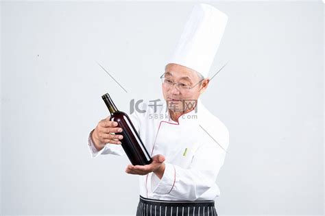 一个老年男人穿着厨师服拿着调味品高清摄影大图-千库网
