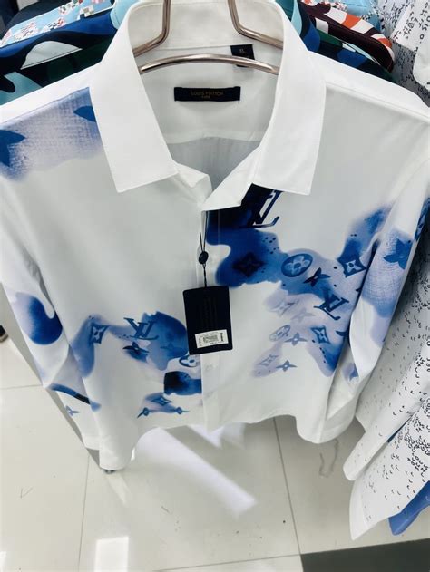 a white shirt with blue and black designs on it in a store display case ...