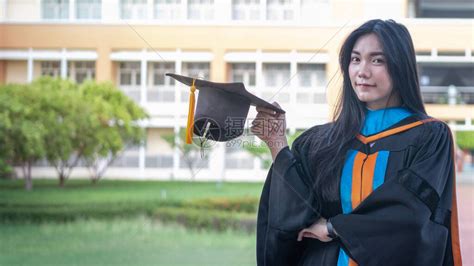 快乐和兴奋的年轻亚洲女大学毕业生的肖像在毕业典礼当天在大学校园里穿着毕业礼服和帽子庆祝学高清图片下载-正版图片504608482-摄图网