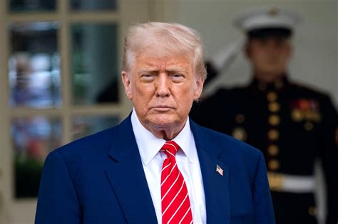 US President Donald Trump, wearing a dark blue suit, white shirt, and light blue tie, looks ahead, h