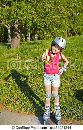 Little girl in roller skates at a park. Little girl in helmet and ...