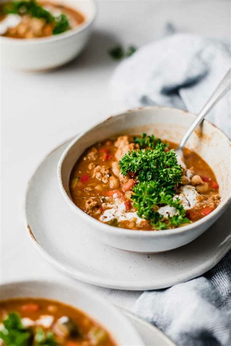 A bowl of Laura's quick slow cooker turkey chili, topped with shredded cheese, sliced green onions,
