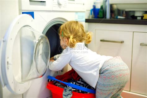可爱的蹒跚学步的女孩从洗衣机里拿干净的衣服高清图片下载-正版图片505826528-摄图网