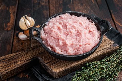 Uncooked raw minced chicken and turkey meat in a pan with herbs. dark ...