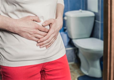 A woman holds her stomach by the toilet. the girl suffers from diarrhea ...