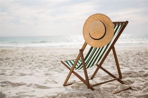 Straw hat kept on empty beach chair | Free Photo