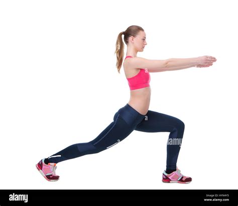 Side view portrait of a young woman stretching leg muscles before exercise workout on isolated ...