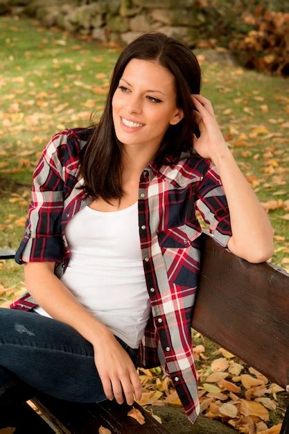 Beautiful young woman sitting in park at fall | Premium Photo