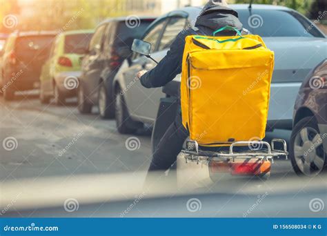 Food Delivery Courier with Big Yellow Backpack Riding Scooter on City ...
