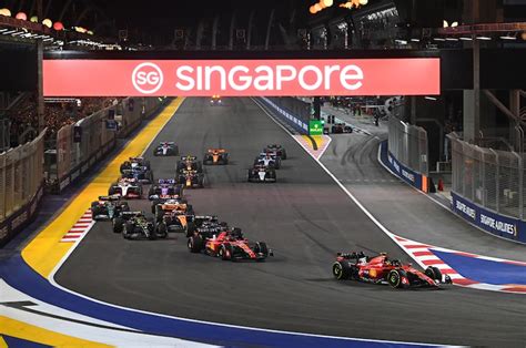 Coches de F1 pasando por el puente de Singapur de noche.